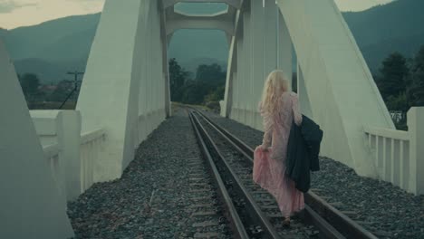 woman walking on train tracks over a bridge