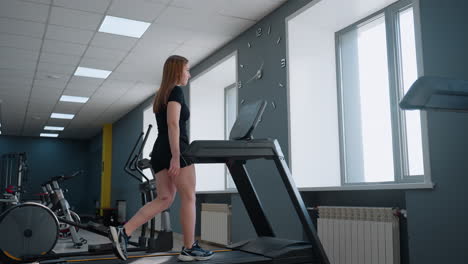 freelancer in casual gym outfit works out on treadmill adjusting speed and incline under bright natural light in modern fitness studio with exercise bikes and elliptical trainer visible behind