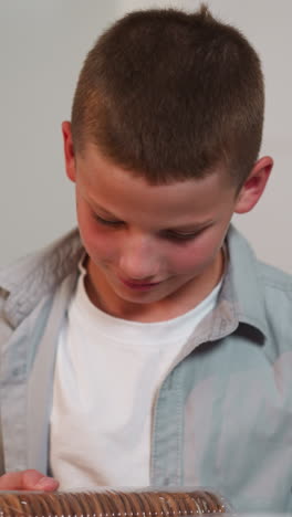 schoolboy looks at mother expectantly standing in kitchen. woman takes out food from bag and gives cookies to son. boy takes treat happily closeup