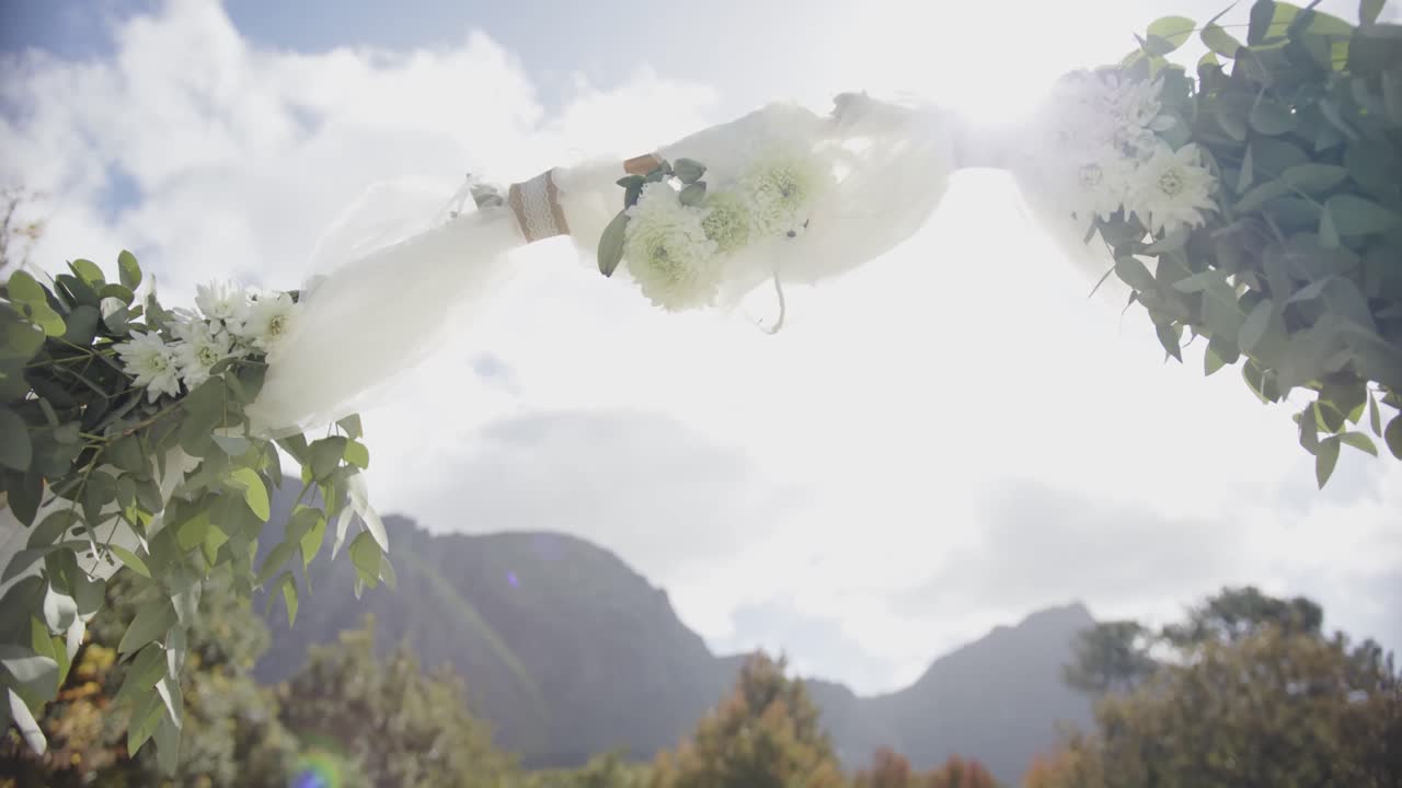 슬로우 모션으로 먼 산과 함께  ⁇ 은 여름 정원에서 꽃 장식과 함께 결혼 아치