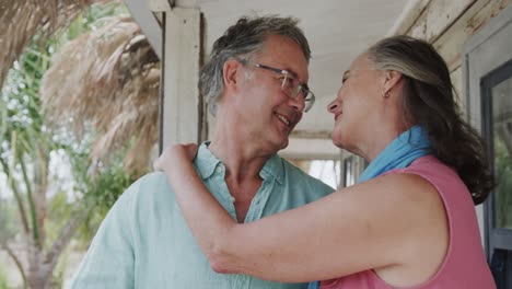 una feliz pareja caucásica hablando y abrazándose en el porche de la casa de la playa, en cámara lenta