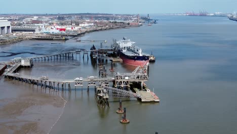 crude oil tanker ship loading at refinery harbour terminal aerial view high pull back