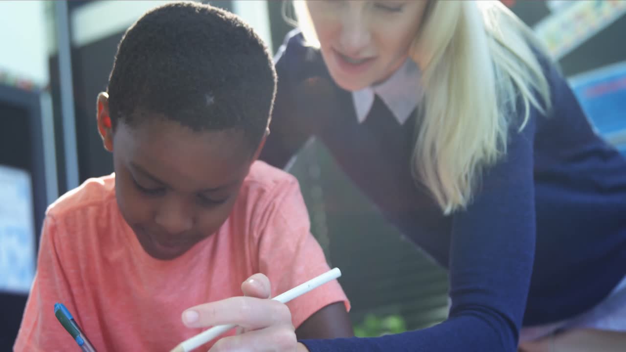 Teacher helping schoolboy with his homework in classroom