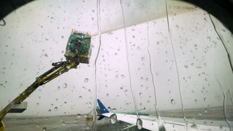 window seat pov from airplane window with de-icing fluid being sprayed overhead