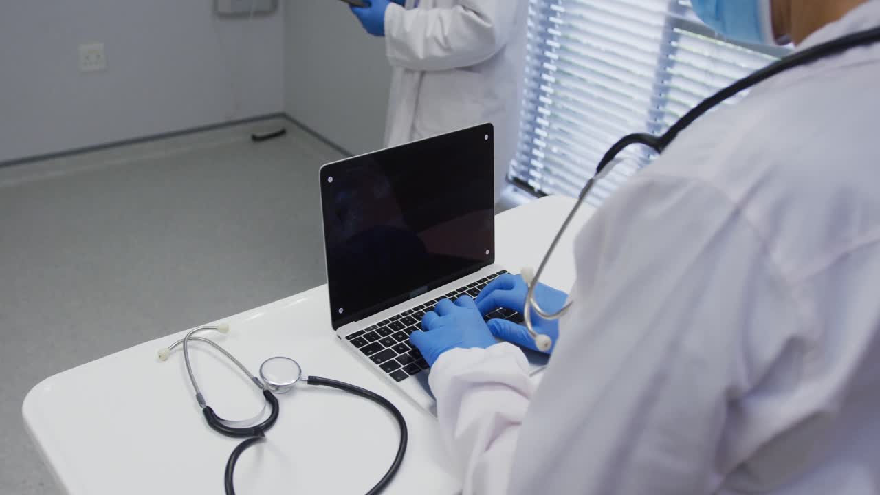 sección media del médico con máscara facial y guantes quirúrgicos usando una computadora portátil, copia el espacio en la pantalla