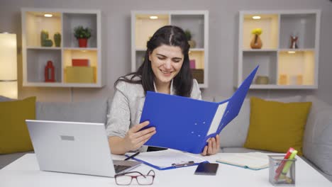 una trabajadora de oficina en casa mirando archivos de papeleo.