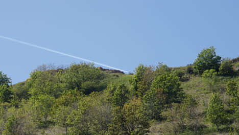 shot of a plane vapour trail, contrail at cardigan bay on cwmtydu beach