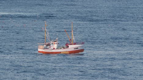 small-white-fishing-boat-sailing-on-a-open-sea-of-northern-norway,-60fps-slow-motion