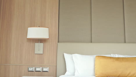 inclinarse hacia abajo desde una cabecera acolchada hasta el lado vacío de una lujosa cama de hotel