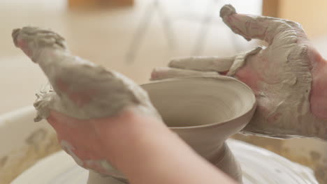 skilled artisan molds delicate vase with practiced hands on a spinning wheel in his studio