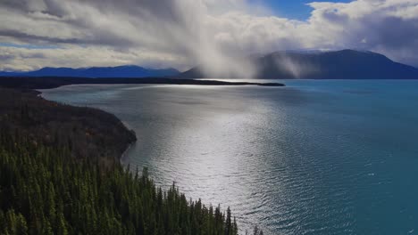 volar sobre el lago atlin junto al lago con rayos de sol a través de las nubes, canadá