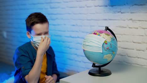 boy looking at globe learning about virus spreading around the world. child with curious face thinking about the planet during covid lock down. concept of covid-19 pandemic infection.