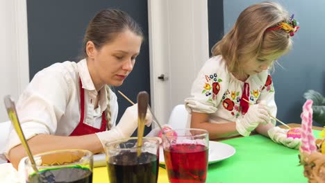 mother and daughter painting easter eggs