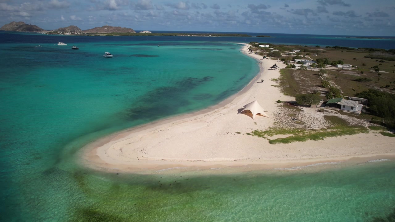 Spiaggia di sabbia bianca con acque limpide e turchesi e piccole tende a Punta Madrisqui a Los Roques.