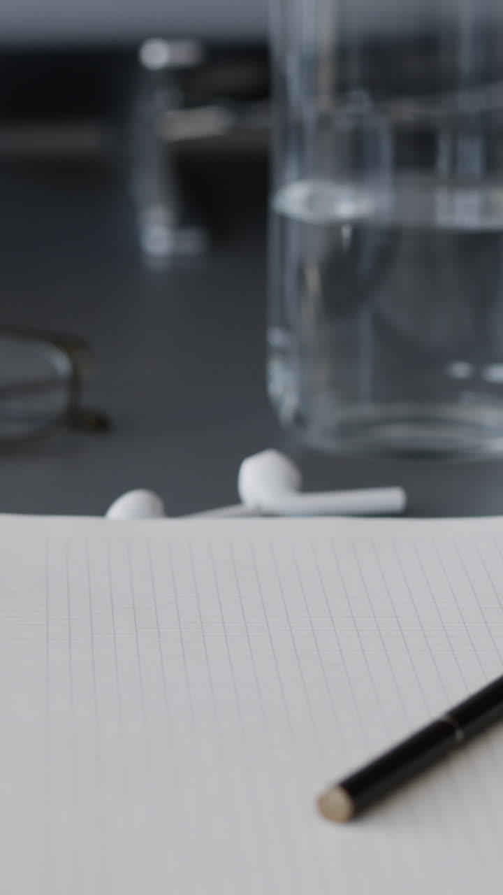 Workspace with notebook, pen, glasses, earbuds, and water bottle