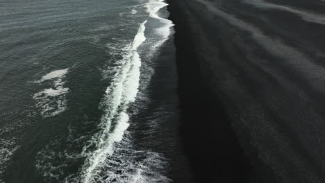 Vista-Aérea-Inclinada-Sobre-Las-Olas-En-La-Playa-De-Arena-Negra-De-Stokksnes,-Día-Sombrío-En-Islandia