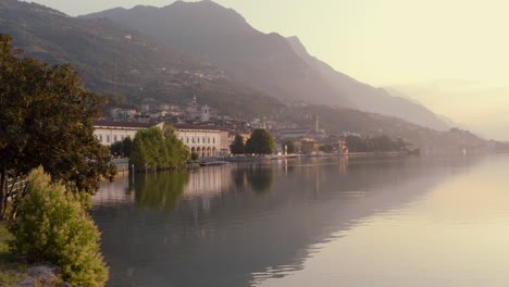 Drone-view-of-Lake-Iseo-at-sunrise,-on-the-left-the-city-of-Lovere-which-runs-along-the-lake,Bergamo-Italy