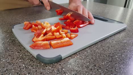 closeup of hands cutting red bell peppers on a chopping board