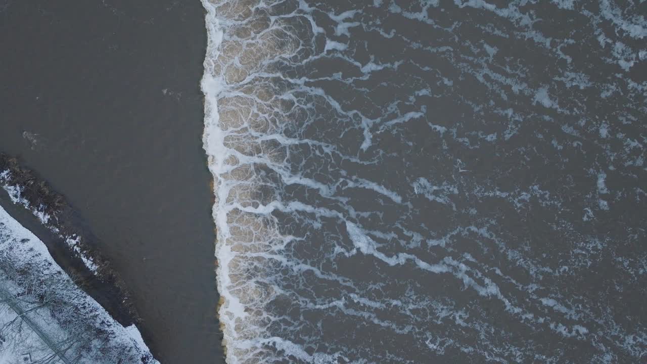 взгляд с воздуха на пороги реки вента во время зимнего наводнения, кулдига, латвия, облачный зимний день, широкий взгляд птичьего глаза с дроном, движущийся вперед