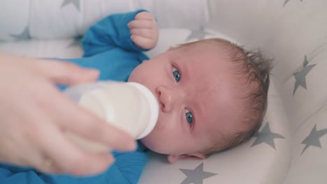 mommy feeds little child with milk mix in comfortable cocoon