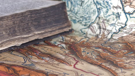 close-up pan of worn old book lying on colorful map, shallow dof