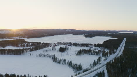 vista aérea a través de vastos asentamientos cubiertos de nieve escandinavos rodeados por el paisaje forestal de laponia bajo el horizonte del amanecer