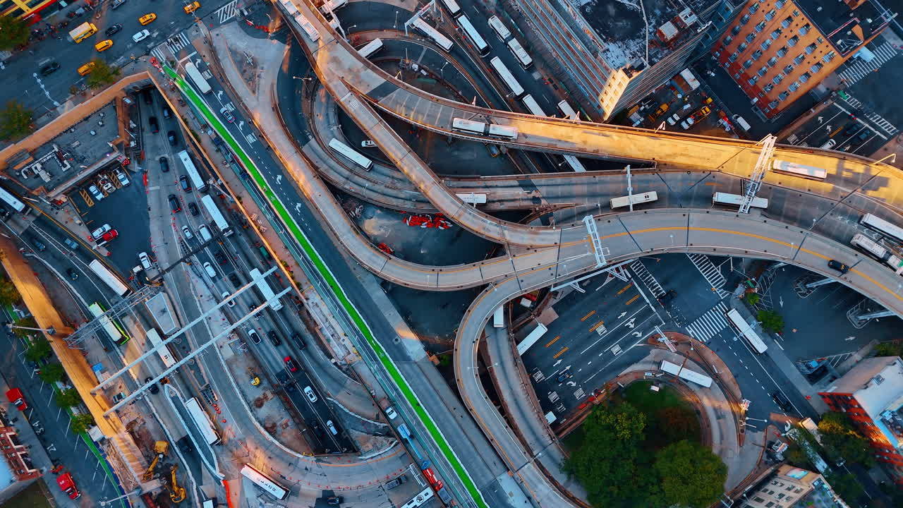 Top view of multi level bus interchange and city streets. Aerial perspective of circular ramps and transit infrastructure with buses and cars during sunset with long shadows