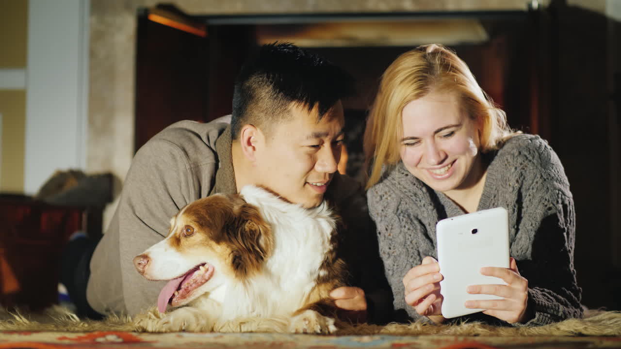 젊은 부부는 개와 함께 벽난로 옆에서 쉬고 있다 02