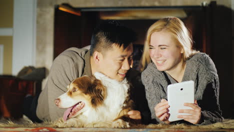 Young-Couple-Rests-By-The-Fireplace-With-Dog-By-Side-02