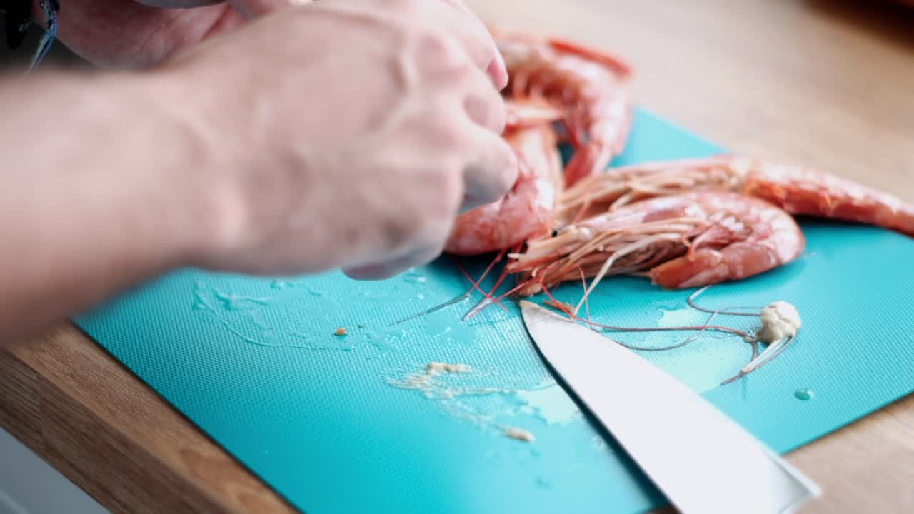 천천히  ⁇ 질을 벗기는 새우: 파란색 보드를 가진 사람이 새우를 청소합니다.