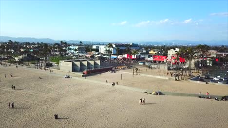 Venice-beach-California-Drone-shot-moving-forward-panning-up-on-beach-front-over-basketball-courts-showing-buildings