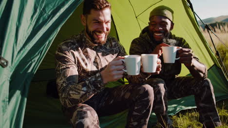 two friends enjoying coffee and laughter in a tent during a camping trip