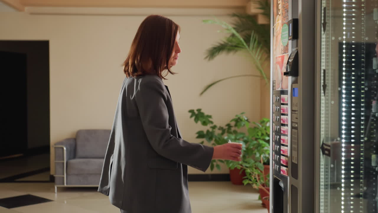 Mujer de negocios eligiendo una bebida de una máquina expendedora en la oficina, pausa informal en la oficina, mujer en traje, usando una máquina expendedora moderna, ambiente de oficina, eligiendo una bebida, hora del descanso