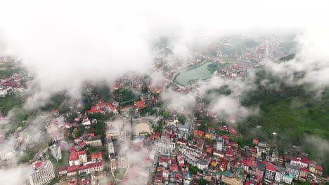 Aerial high angle overview establishes cloudy morning over Sapa, village and hills hidden in misty atmosphere