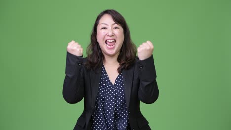 mature happy asian businesswoman with fists raised