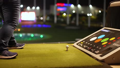 woman playing golf at a driving range at night
