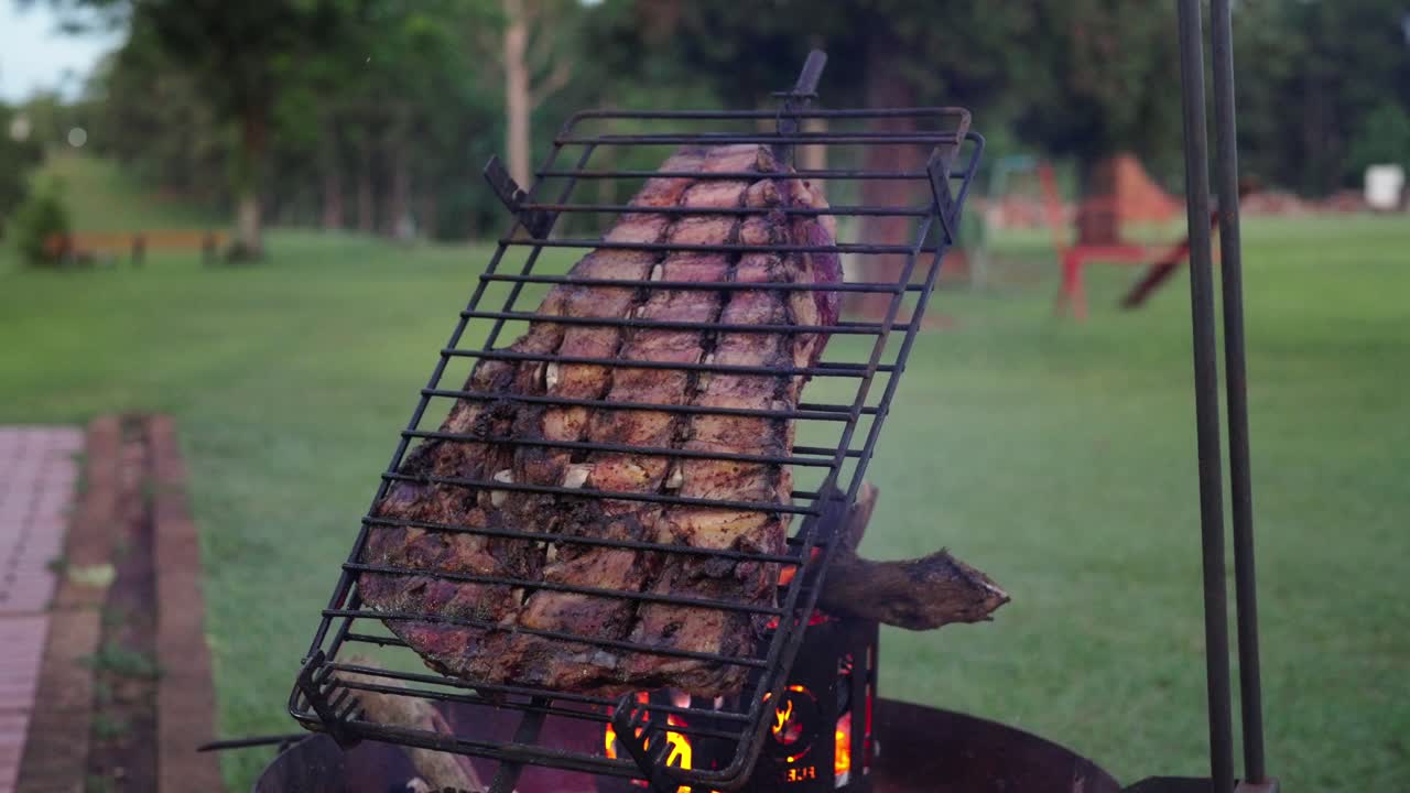 Close up of Argentinian barbecue scene with large ribs cuts cooking on grill, culinary latin culture