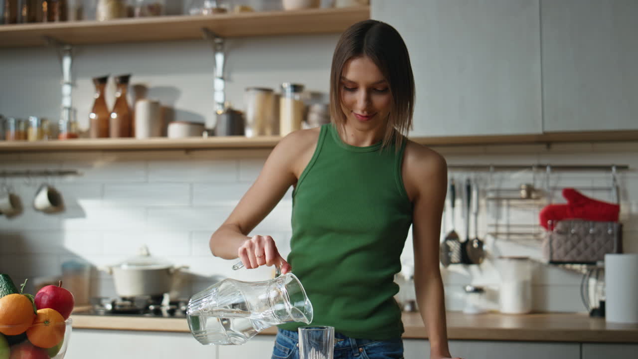 mujer bebiendo agua en la cocina