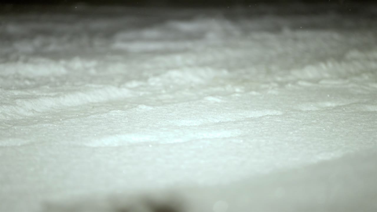 Bokeh shot of slow motion snowflakes falling on a snow covered ground, winter weather, static shot, copy space