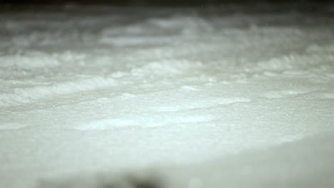 bokeh shot of slow motion snowflakes falling on a snow covered ground, winter weather, static shot, copy space