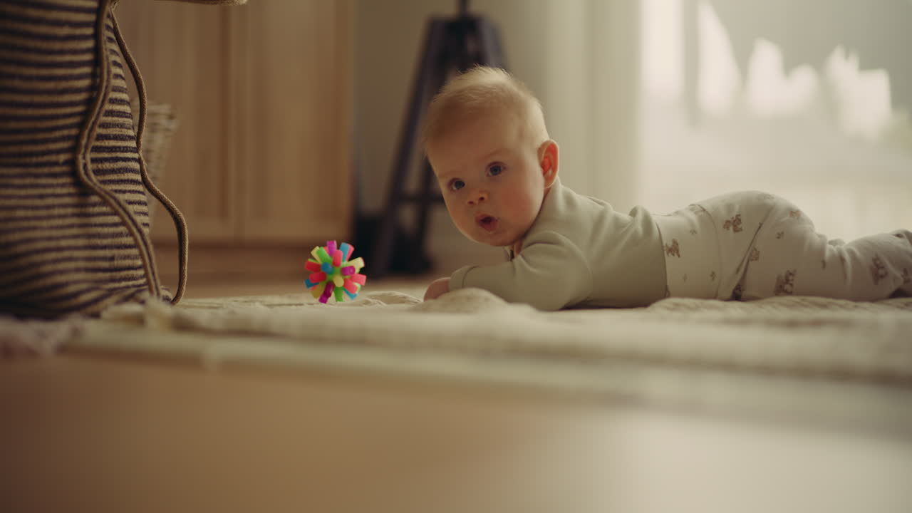 Baby lying on carpet playing with toy