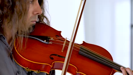 cerrar el perfil de un músico hispano con pelo largo y perilla tocando viola roja