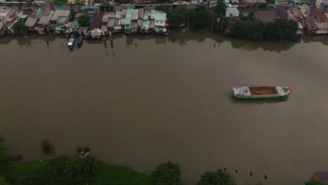 foggy,smoggy early morning drone footage tracking a working boat from the mekong delta along a major canal in saigon, ho chi minh city, vietnam