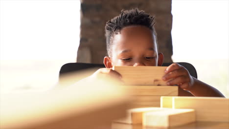 panning shot of young child playing with blocks enjoying himself