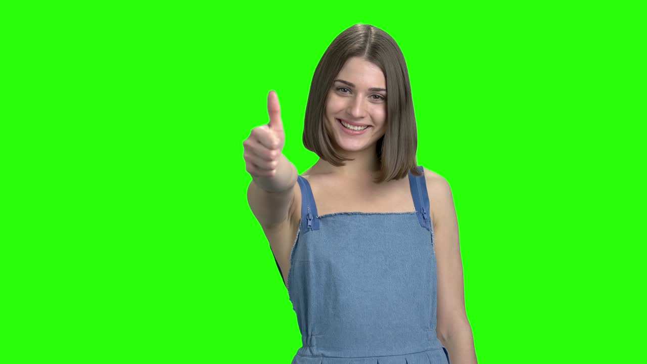 una joven morena con un vestido de vaquero muestra el pulgar hacia arriba.