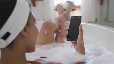 Mujer-De-Raza-Mixta-Tomando-Un-Baño-Y-Usando-Un-Teléfono-Inteligente