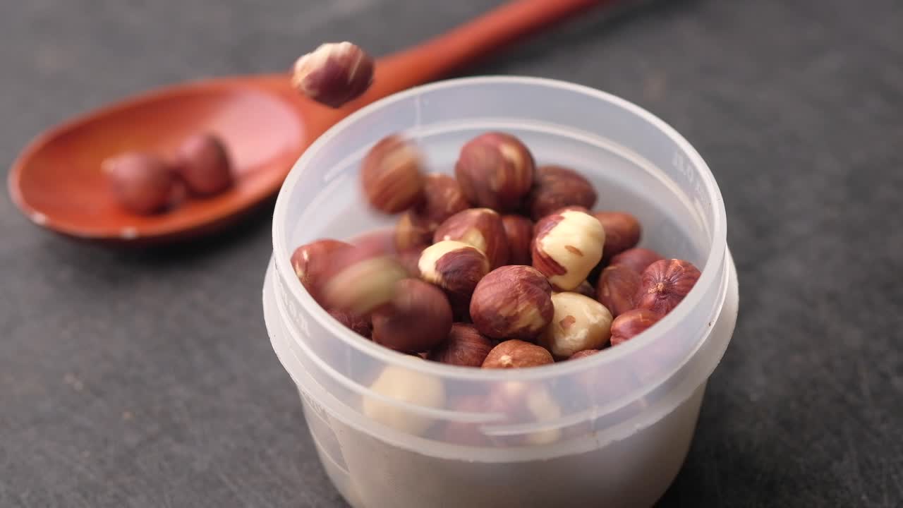 Hazelnuts in a Container and Wooden Spoon