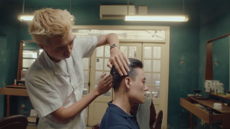 asian barber using styling powder on hair of client