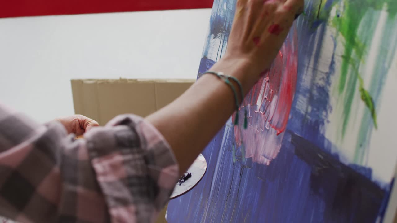 video de las manos de una artista femenina biracial pintando en el estudio