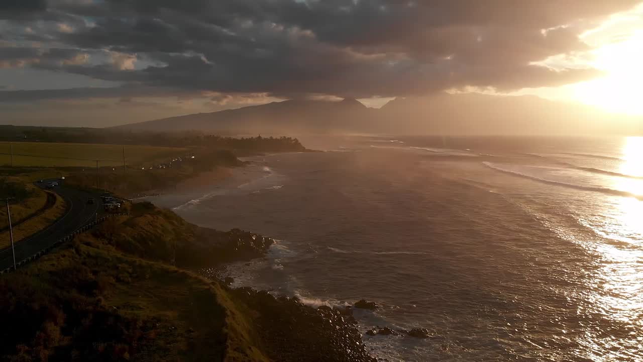 A drone flies over the Maui, Hawaii north shore capturing images near Ho'okipa beach and Paia at sunset.